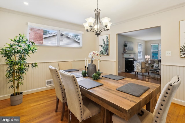 1407 Crestridge Dr, Silver Spring, MD 20910 - dining room featuring a wainscoted wall, light wood-type flooring, a chandelier, a fireplace, and ornamental molding