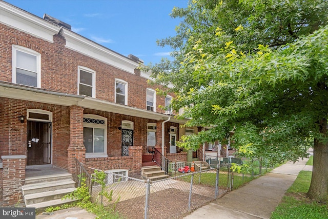1635 Montpelier St, Baltimore, MD 21218 - view of property featuring a porch, a gate, brick siding, and a fenced front yard