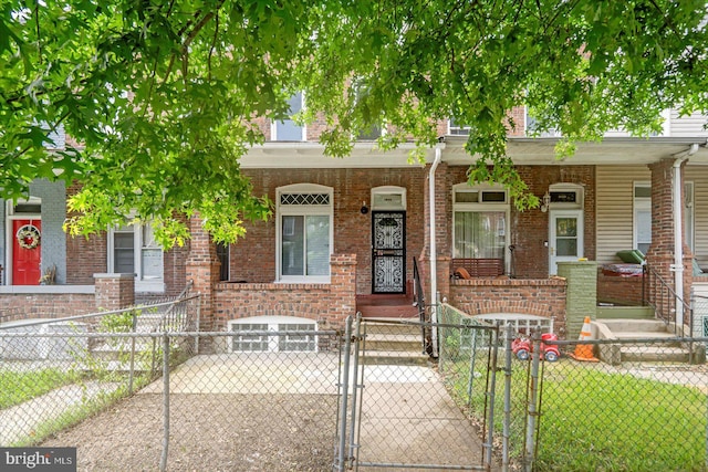 1635 Montpelier St, Baltimore, MD 21218 - view of property with a porch, a gate, a fenced front yard, and brick siding