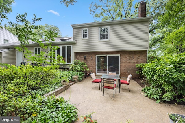 8306 Winslow Ave, Springfield, VA 22152 - rear view of house featuring brick siding, a patio area, a chimney, and outdoor dining area