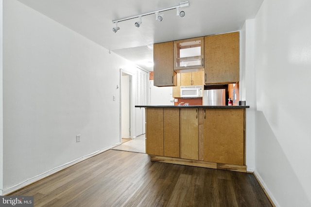 2030 F St NW Unit 111, Washington, DC 20006 - kitchen with white microwave, refrigerator, wood finished floors, rail lighting, and dark countertops