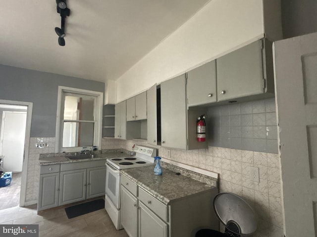 1115 E 11th St, Crum Lynne, PA 19022 - kitchen featuring white range with electric cooktop, tile walls, gray cabinets, light tile patterned floors, and backsplash