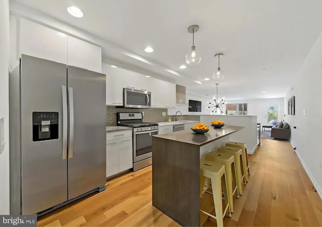 2538 W Girard Ave Unit A, Philadelphia, PA 19130 - kitchen featuring appliances with stainless steel finishes, white cabinets, a breakfast bar, a center island, and decorative backsplash