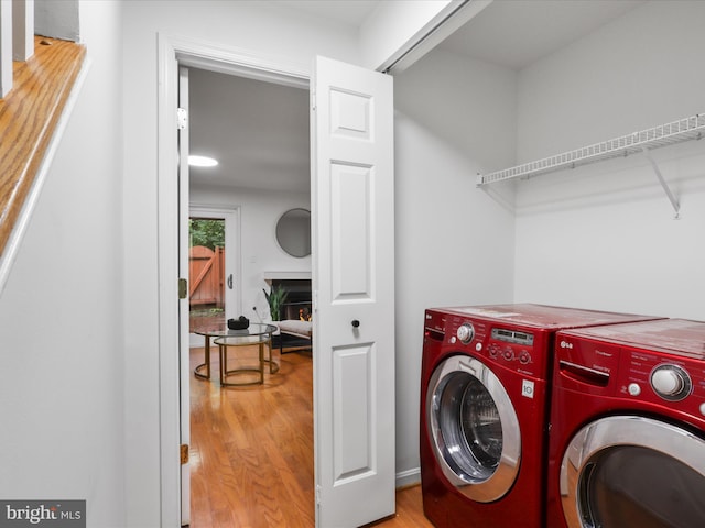 6427 Brass Button Ct, Centreville, VA 20121 - washroom with washing machine and clothes dryer, wood finished floors, and a warm lit fireplace