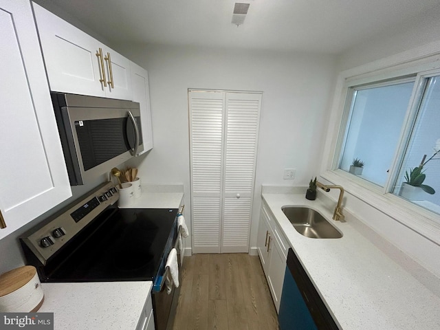 1239 Guildford Rd, Glen Burnie, MD 21060 - kitchen featuring appliances with stainless steel finishes, light wood-type flooring, white cabinets, and light stone counters