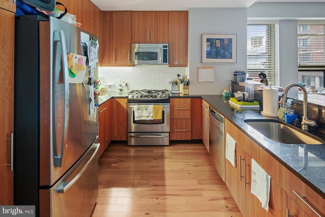 1425 Locust St Unit 5C, Philadelphia, PA 19102 - kitchen featuring stainless steel appliances, dark stone counters, brown cabinets, light wood-style flooring, and tasteful backsplash