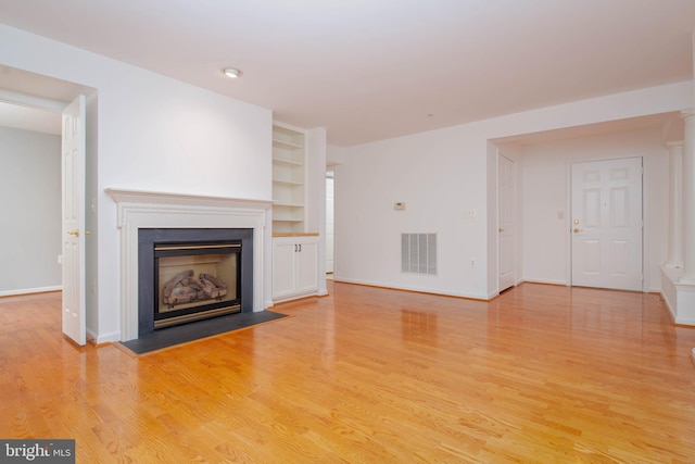 12030 Tralee Rd Unit 306, Lutherville Timonium, MD 21093 - unfurnished living room with light wood-style floors, a fireplace with flush hearth, and built in shelves