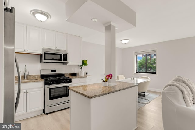 1200 S Arlington Ridge Rd Unit 507, Arlington, VA 22202 - kitchen with stainless steel appliances, light stone counters, white cabinetry, and light wood-style floors