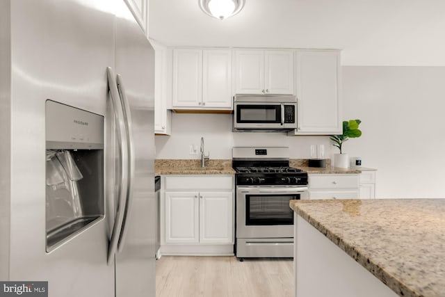 1200 S Arlington Ridge Rd Unit 507, Arlington, VA 22202 - kitchen featuring appliances with stainless steel finishes, white cabinetry, light stone countertops, and light wood-type flooring