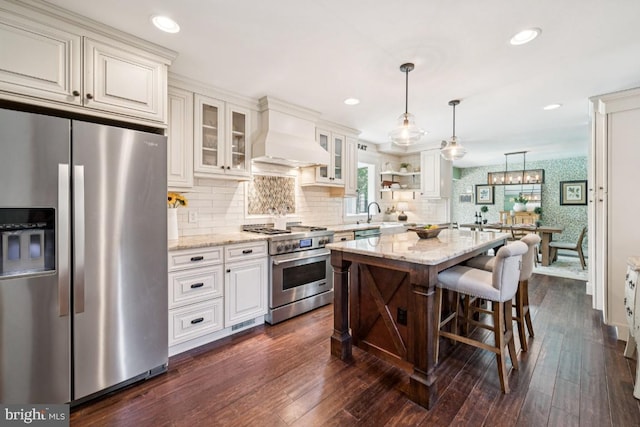 236 Carriage Hill Dr, Moorestown, NJ 08057 - kitchen with stainless steel appliances, wallpapered walls, premium range hood, light stone countertops, and decorative light fixtures