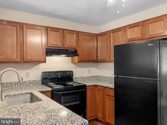 2635 Limestone Ct, Winchester, VA 22601 - kitchen with black appliances, under cabinet range hood, brown cabinets, light stone counters, and a textured ceiling