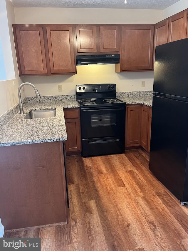 2635 Limestone Ct, Winchester, VA 22601 - kitchen featuring black appliances, under cabinet range hood, dark wood finished floors, and light stone countertops