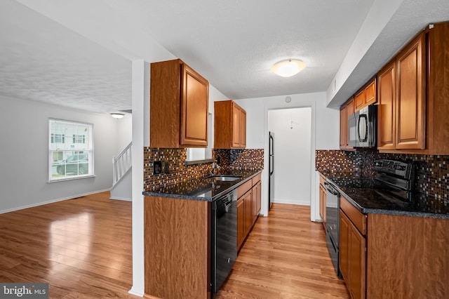 2 Brookshire Dr Unit A, Reisterstown, MD 21136 - kitchen with black appliances, a textured ceiling, brown cabinetry, light wood finished floors, and tasteful backsplash
