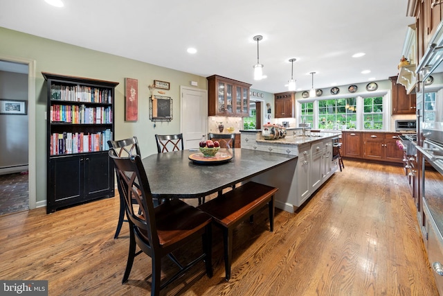 4105 Meadow Ln, Newtown Square, PA 19073 - kitchen featuring light wood-type flooring, glass insert cabinets, recessed lighting, decorative light fixtures, and light stone counters