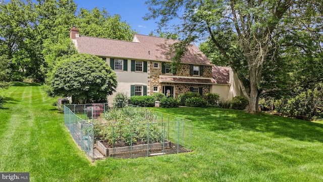 4105 Meadow Ln, Newtown Square, PA 19073 - rear view of house featuring a vegetable garden, stucco siding, a chimney, and a lawn