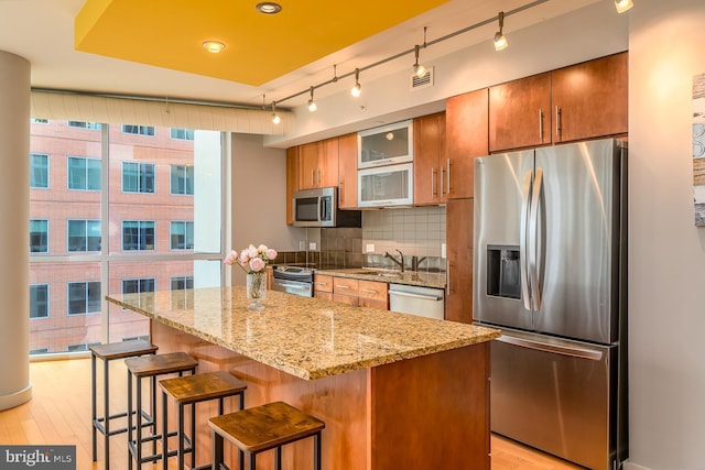 1025 1st St SE Unit 713, Washington, DC 20003 - kitchen with stainless steel appliances, tasteful backsplash, a kitchen island, track lighting, and light wood-type flooring