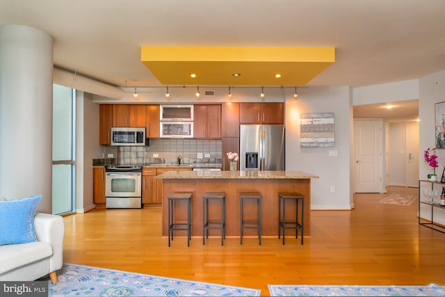 1025 1st St SE Unit 713, Washington, DC 20003 - kitchen featuring appliances with stainless steel finishes, light wood-style floors, rail lighting, brown cabinetry, and a breakfast bar area