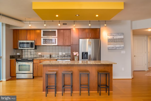 1025 1st St SE Unit 713, Washington, DC 20003 - kitchen featuring stainless steel appliances, track lighting, brown cabinetry, and light wood-type flooring