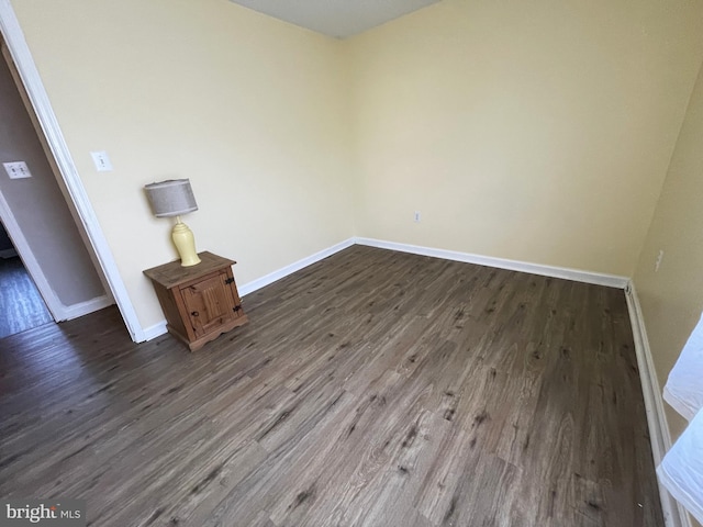 103 N W St, Harrington, DE 19952 - spare room featuring dark wood-type flooring and baseboards
