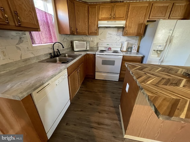 103 N W St, Harrington, DE 19952 - kitchen featuring white appliances, under cabinet range hood, brown cabinetry, dark wood-style flooring, and tasteful backsplash
