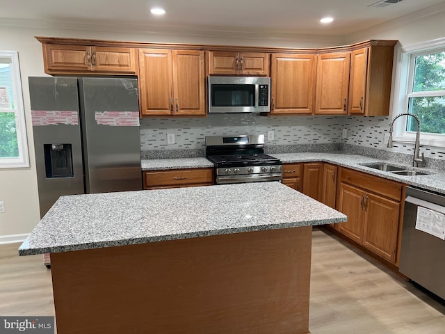 14503 Melbourne Ave, Woodbridge, VA 22191 - kitchen with stainless steel appliances, crown molding, light wood-style flooring, brown cabinetry, and light stone counters
