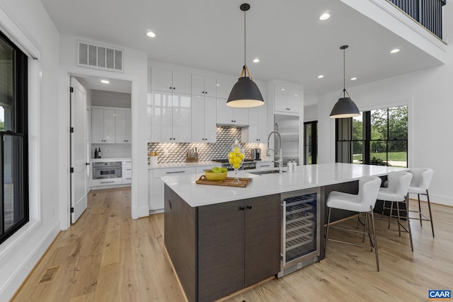 310 Goodloe Ln, Afton, VA 22920 - kitchen with beverage cooler, white cabinets, tasteful backsplash, light wood-style floors, and recessed lighting