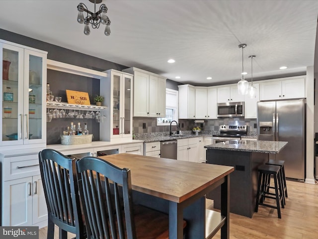 443 Executive Way, Hedgesville, WV 25427 - kitchen with stainless steel appliances, white cabinetry, a breakfast bar, glass insert cabinets, and decorative light fixtures