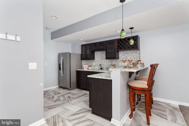 173 Empress Alexandra Pl, Fredericksburg, VA 22406 - kitchen with stainless steel fridge, a kitchen breakfast bar, glass insert cabinets, dark brown cabinetry, and a peninsula