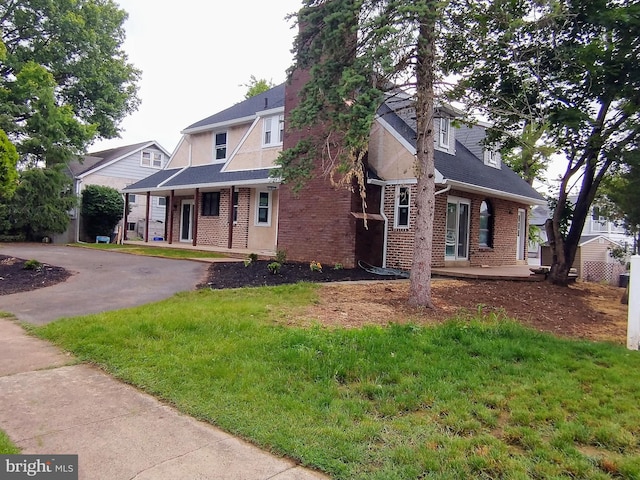 512 Mifflin Blvd, Reading, PA 19607 - tudor-style house with brick siding, a front yard, covered porch, and roof with shingles