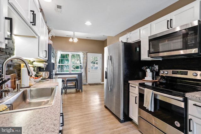 309 Legion St, Martinsburg, WV 25404 - kitchen featuring stainless steel appliances, white cabinetry, light countertops, light wood-style flooring, and tasteful backsplash
