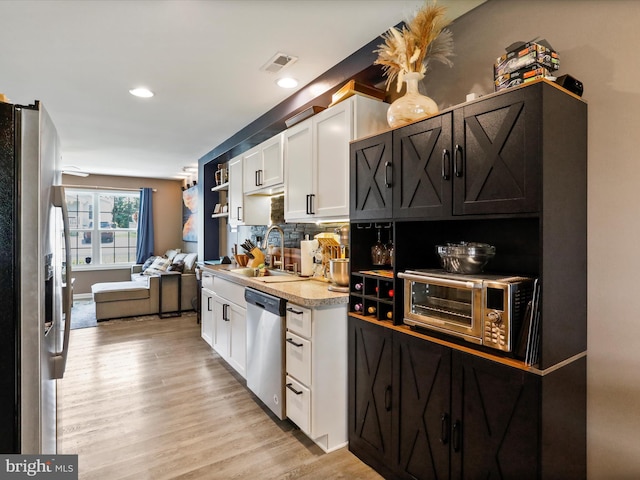 309 Legion St, Martinsburg, WV 25404 - kitchen with stainless steel appliances, white cabinetry, light countertops, light wood-type flooring, and tasteful backsplash