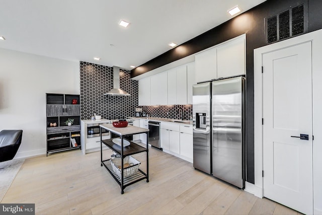 1532 N Capitol NW Unit 402, Washington, DC 20002 - kitchen with appliances with stainless steel finishes, wall chimney range hood, backsplash, white cabinetry, and light wood-style flooring