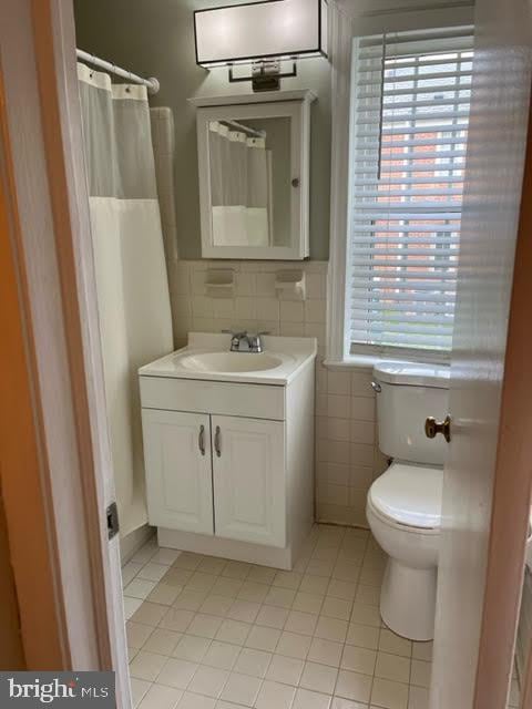 2803 Arlington Blvd Unit 130, Arlington, VA 22201 - full bathroom featuring tile patterned flooring, tile walls, vanity, healthy amount of natural light, and a shower with curtain
