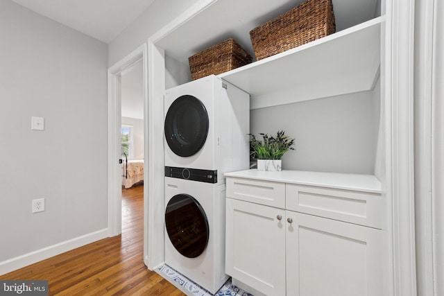 121 Harrison St NE, Leesburg, VA 20176 - laundry area featuring stacked washer and clothes dryer, light wood finished floors, and cabinet space
