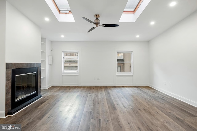 1805 Chestnut St, Philadelphia, PA 19103 - unfurnished living room with a skylight, wood finished floors, ceiling fan, a tile fireplace, and recessed lighting