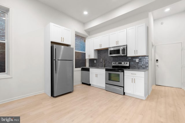 1805 Chestnut St, Philadelphia, PA 19103 - kitchen with appliances with stainless steel finishes, decorative backsplash, white cabinetry, light wood-style flooring, and recessed lighting