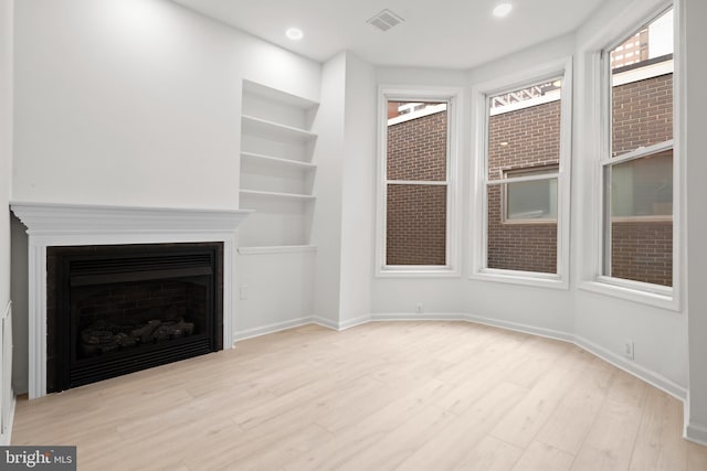 1805 Chestnut St, Philadelphia, PA 19103 - unfurnished living room with wood finished floors, built in shelves, a fireplace, and recessed lighting