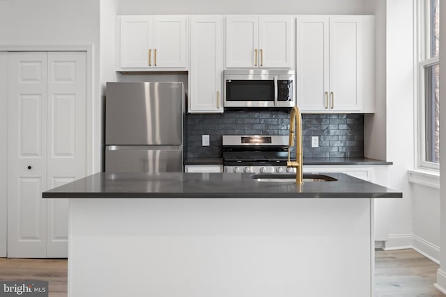 1805 Chestnut St, Philadelphia, PA 19103 - kitchen with stainless steel appliances, dark countertops, white cabinetry, light wood-type flooring, and tasteful backsplash