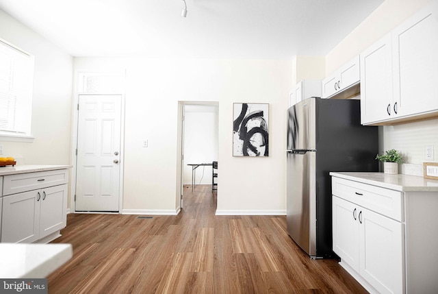 535 N Decker Ave, Baltimore, MD 21205 - kitchen with freestanding refrigerator, wood finished floors, light countertops, and white cabinetry