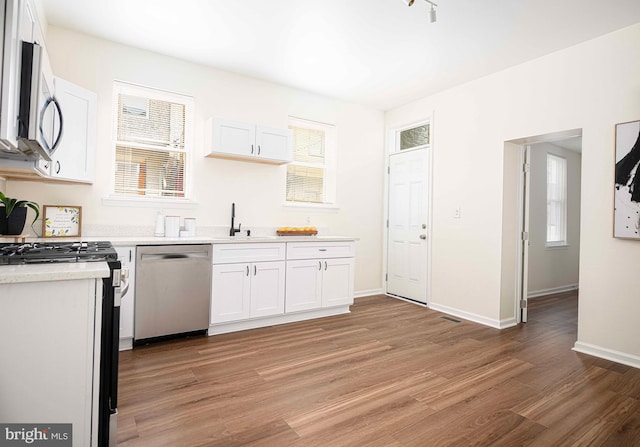 535 N Decker Ave, Baltimore, MD 21205 - kitchen with stainless steel appliances, light wood-style flooring, white cabinets, light countertops, and healthy amount of natural light