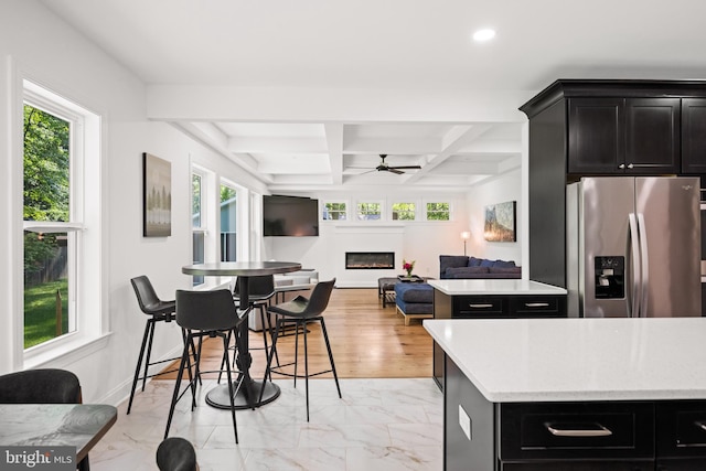 1227 Cross Rd, Annapolis, MD 21403 - kitchen with stainless steel fridge, a glass covered fireplace, ceiling fan, dark cabinetry, and healthy amount of natural light