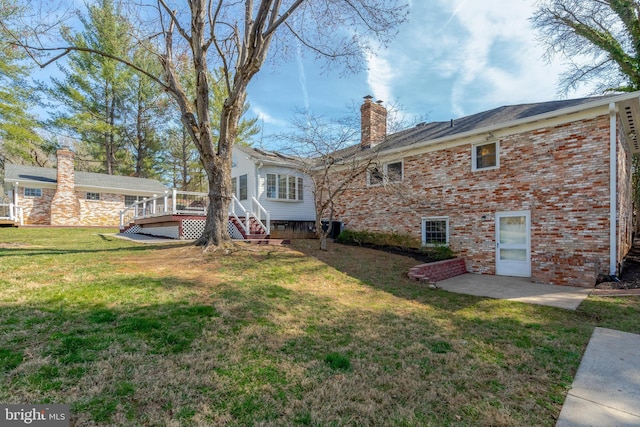 10828 Moore Dr, Manassas, VA 20111 - rear view of property featuring a chimney, brick siding, a wooden deck, a yard, and a patio area