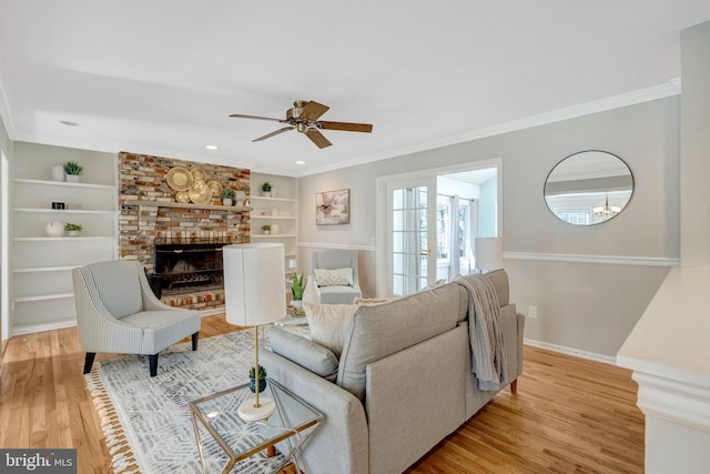 10828 Moore Dr, Manassas, VA 20111 - living room with light wood-type flooring, built in shelves, ceiling fan, a fireplace, and crown molding