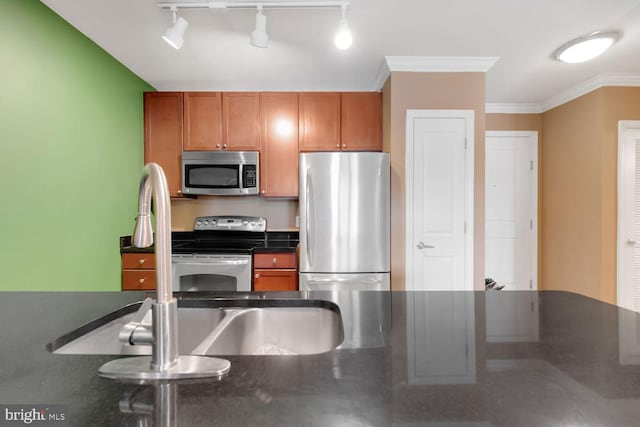 1391 Pennsylvania Ave SE Unit 247, Washington, DC 20003 - kitchen with stainless steel appliances, dark countertops, brown cabinets, rail lighting, and ornamental molding