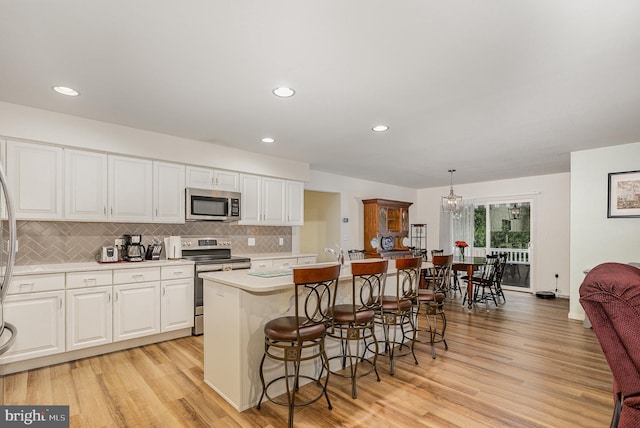 2069 Spring Wood Ln, Mechanicsburg, PA 17055 - kitchen with stainless steel appliances, light countertops, decorative backsplash, a center island with sink, and white cabinets