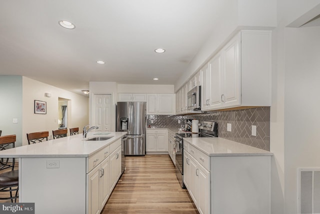2069 Spring Wood Ln, Mechanicsburg, PA 17055 - kitchen with stainless steel appliances, a breakfast bar area, white cabinetry, light countertops, and recessed lighting