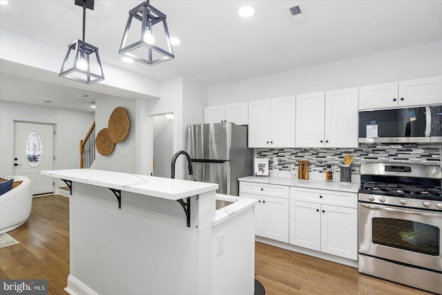 903 Mount Holly St, Baltimore, MD 21229 - kitchen featuring appliances with stainless steel finishes, light wood-style floors, white cabinets, decorative backsplash, and recessed lighting