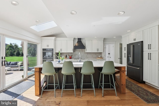1118 Dorset Dr, West Chester, PA 19382 - kitchen featuring black fridge, wall chimney range hood, a skylight, light countertops, and decorative backsplash