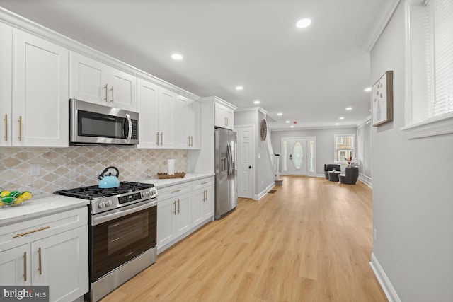 7632 Fayette St, Philadelphia, PA 19150 - kitchen with stainless steel appliances, backsplash, white cabinetry, light wood-style flooring, and ornamental molding