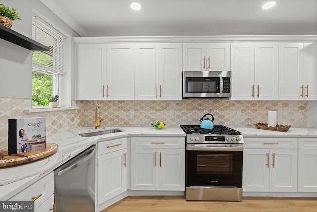 7632 Fayette St, Philadelphia, PA 19150 - kitchen with appliances with stainless steel finishes, white cabinets, crown molding, light wood-type flooring, and light stone countertops